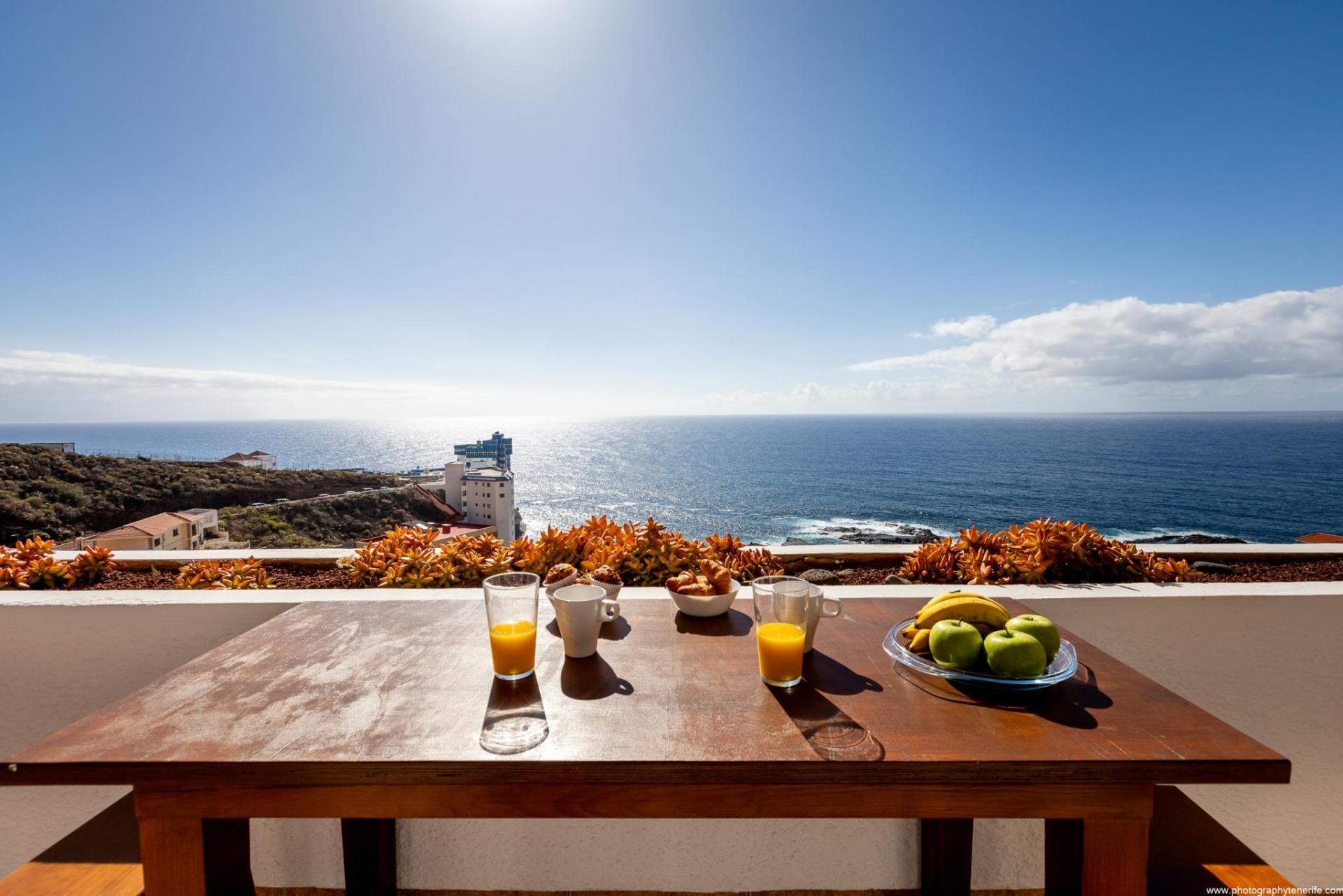 Vista al mar desde la terraza de una propiedad vacacional en alquiler, con mesa de madera desde donde se puede observar el azul inmenso del cielo